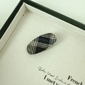 Vista dettagliata di un fermaglio per capelli ovale con classico tessuto tartan grigio e nero - Plaid Nero Ovale
