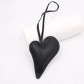 Detailed view of black heart-shaped leather charm with litchi texture and stitching - Black
