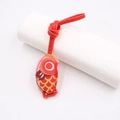 Dettaglio di un ciondolo a forma di carpa koi in pelle rossa con motivi dorati - Cordino Koi