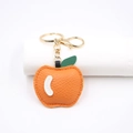 Detailed view of orange faux leather apple keychain with green leaf and gold hardware - Orange