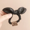 Elegante elastico per capelli con fiocco in ecopelle nera ed etichetta in tessuto marrone - Nero