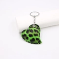 Macro shot of green leopard print heart-shaped leather keychain with silver metal ring - Green