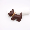 Detail eines dunkelbraunen Leder-Terrier-Taschenanhängers mit hellen Nähten und Goldschnalle - Braun
