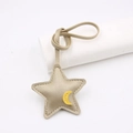 Dettaglio del ciondolo per borsa in pelle a stella con luna gialla e trama lychee - Stella della Buonanotte / Oro