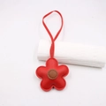 Close-up of red leather flower bag charm with brown center and detailed stitching texture - Red