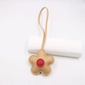 Close-up of a floral leather bag charm with cream petals and a red center detail - Khaki