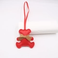 Close-up of a red litchi texture faux leather bear charm with a khaki bow and long lanyard - Red