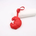 Detail of red leather croissant charm showing precise stitching and padded texture finish - Red