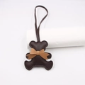 Close-up of brown leather bear charm with fine stitching and matching neck bow - Brown