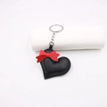 Handmade leather heart keychain with a red bow and silver metal ring on white background - Black