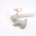 Macro detail of a grey pebbled leather puppy keychain with gold hardware and fine stitching - Gray