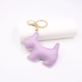 Macro view of purple leather dog bag charm with detailed stitching and gold key ring - Taro Purple