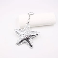 Close-up of sparkling silver star leather keychain with metallic ring and chain - Pentagram / Silver