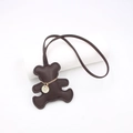 Dark brown leather bear bag charm with gold chain and pendant on a white background - Brown