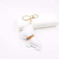Detailed close-up of white leather bulldog keychain with gold metal clasp and stitching - White