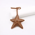 Détail d'un pendentif étoile de mer en cuir avec rivets dorés et coutures fines sur fond blanc - Rivet Étoile de Mer (zg 001) / Marron