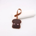 Close-up of a cute brown toast leather charm with cartoon expression and hanging strap - Brown