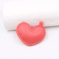 Detail of coral pink heart leather charm with lychee texture and hand-stitched edges - Rose Red