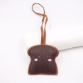 Dettaglio del ciondolo in pelle a forma di pane con trama intrecciata e viso sorridente - Brown Smile