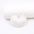 Dettaglio di un accessorio in pelle bianca a forma di cuore con cuciture e anello metallico - Bianco