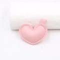 Dettaglio di un ciondolo a cuore in ecopelle rosa con cuciture rifinite e passante - Rosa