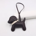 Close-up of a brown leather puppy bag charm with white stitching and a long strap - Dark Brown - Beige Collar
