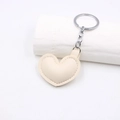 Dettaglio portachiavi a cuore in pelle beige con catena in metallo argento e cuciture - Beige