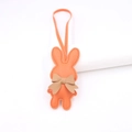 Detail von orangefarbenem Lederhasen-Anhänger mit khakifarbener Schleife und Nähten - Orange