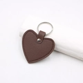 Close-up of heart-shaped dark brown leather keychain with silver rivet and metallic ring - Heart Keychain / Brown