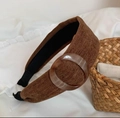 Detail view of brown corduroy headband with a large amber resin buckle on white fabric - Brown