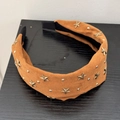 Dettaglio del cerchietto in camoscio beige con stelle dorate e rivetti in metallo - Arancione
