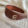 Close-up of brown faux leather headband with rhinestone letter E and fine stitching - Rhinestone Letter Decoration (E) / Brown
