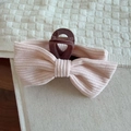 Gros plan d'une pince à cheveux avec nœud en tissu rose texturé à motif côtelé - Rose Clair
