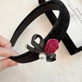 Dettaglio del cerchietto in velluto con rosa rosso scuro, fiocco nero e perla finta - Cerchietto