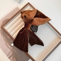 Détail d'une pince à cheveux en velours marron avec nœud et accent doré sur plateau - Marron