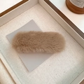 Macro shot of fluffy camel plush oval hair clip on textured display card for winter - Brown