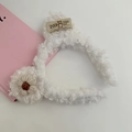 Detail van witte pluche hoofdband met gebreide bloem en vintage stoffen label met beer - Wit
