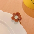 Primo piano di una mini pinza per capelli a fiore marrone su un piatto decorativo in porcellana - Caffè Floreale