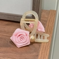 Dettaglio ravvicinato di una pinza per capelli con rosa in tessuto e perle sintetiche - Rosa