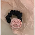 Detailansicht eines schwarzen Plissee-Haargummis mit einer rosa Satinrose - Rosa Rose