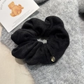 Close-up of black oversized fabric scrunchie with detailed gold circular metal pendant charm - Black Hair Tie