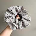 Detail of oversized fabric scrunchie with metallic splash dots texture held in hand - Gray Spotted Style