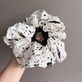Close-up of oversized white scrunchie with ink splatter pattern and Fashion woven label - Beige Spotted Style