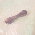 Close-up of translucent purple acetate face massage tool on white paper texture - Purple