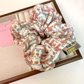 Detailed shot of tweed hair scrunchie with woven label and orange-blue knit texture - Orange And Blue Contrast (D-4449-2)