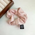 Pink waffle texture scrunchie with floral label shown on a warm wooden aesthetic background - Pink