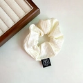 Macro shot of white waffle knit scrunchie featuring a black woven tag with camellia logo - Beige