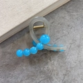 Pinza para el pelo translúcida con cuentas azules y resorte dorado sobre fondo piedra - Azul