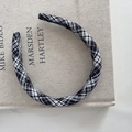 Détail d'un serre-tête en tissu à carreaux noir et blanc sur une couverture de livre texturée - Carreaux Noir et Blanc avec Nœud Rouge
