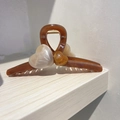 Detail of amber translucent heart hair claw clip with golden metal spring on wood - Brown